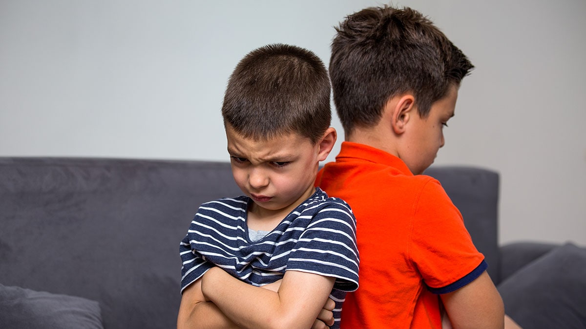 Two frustrated boys sitting back-to-back.