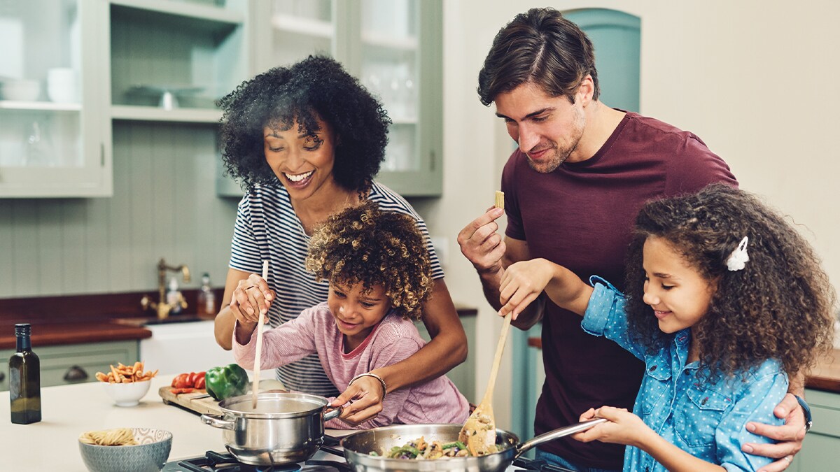 Padres cocinando con sus dos hijas en la cocina.