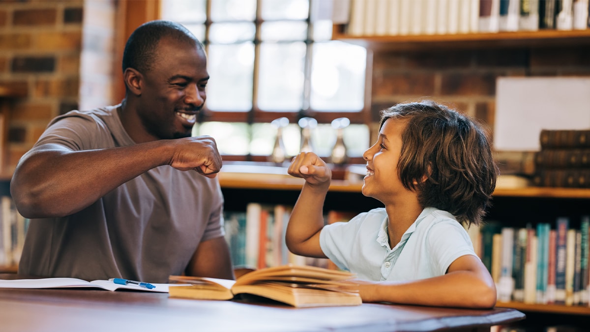 educator with student high fiving in library