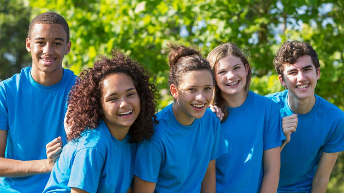 Young teens volunteering outside and smiling at camera