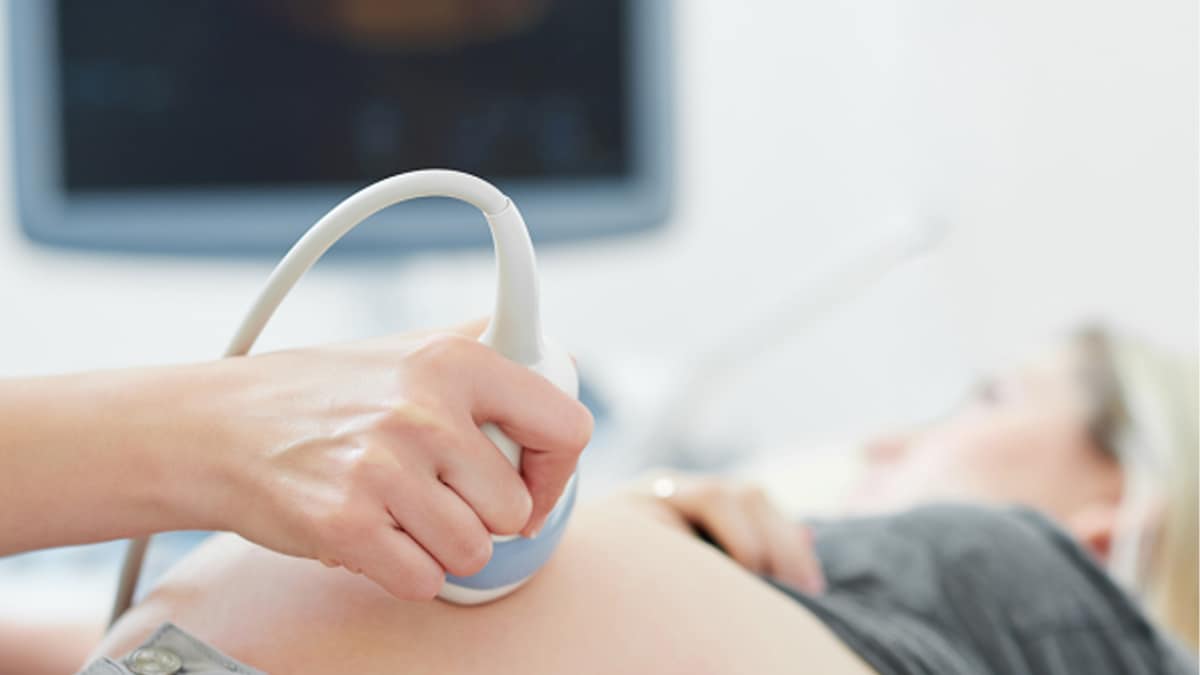 Doctor using ultrasound machine on pregnant woman