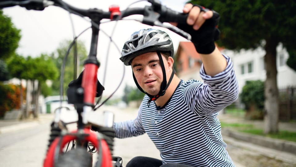 Teen with Down syndrome looking at their bike.