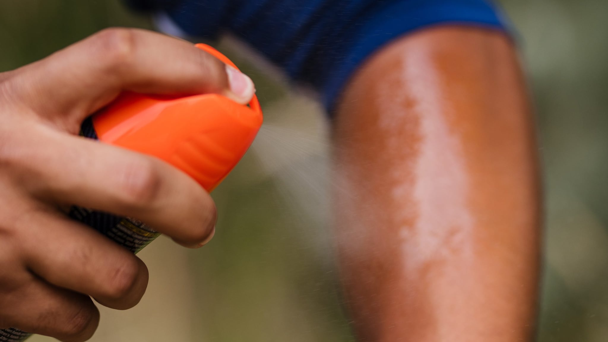 Person spraying insect repellent onto their arm.