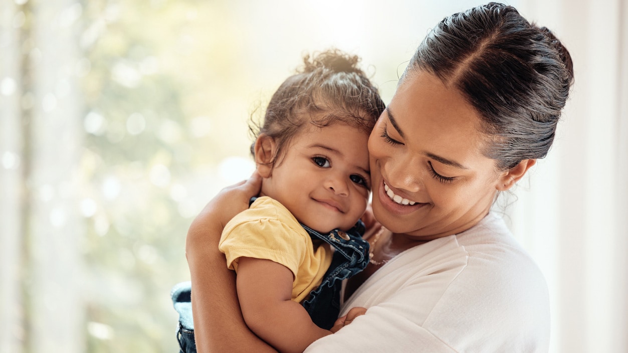 A mom hugs her young daughter.