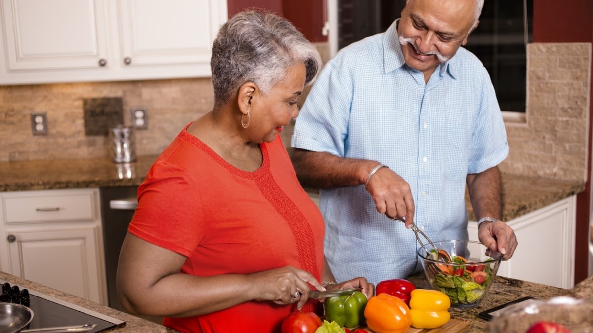 Photo of a couple in a kitchen making a salad