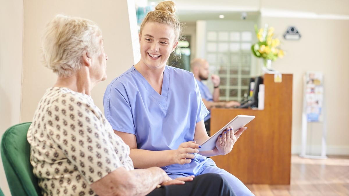 A patient navigator speaks to an older woman at a doctor's office