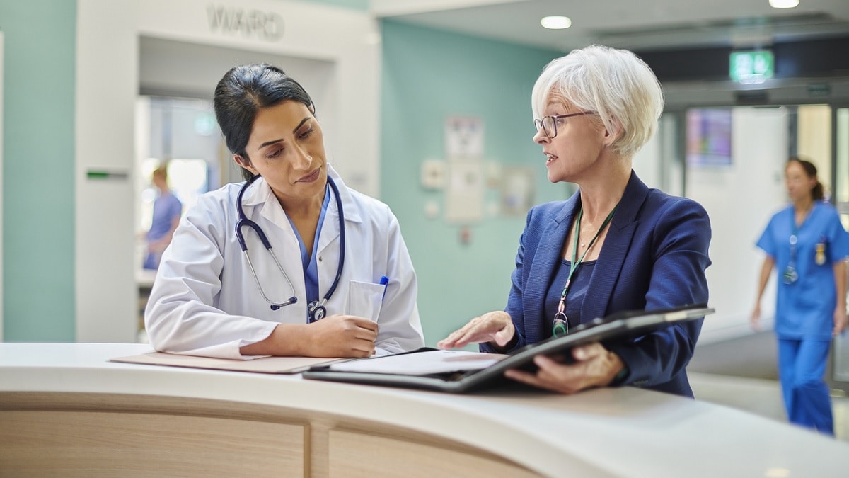 A hospital administrator reviews a report with a doctor