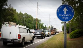 Cars driving on a road with a sign saying "Evacuation Route"