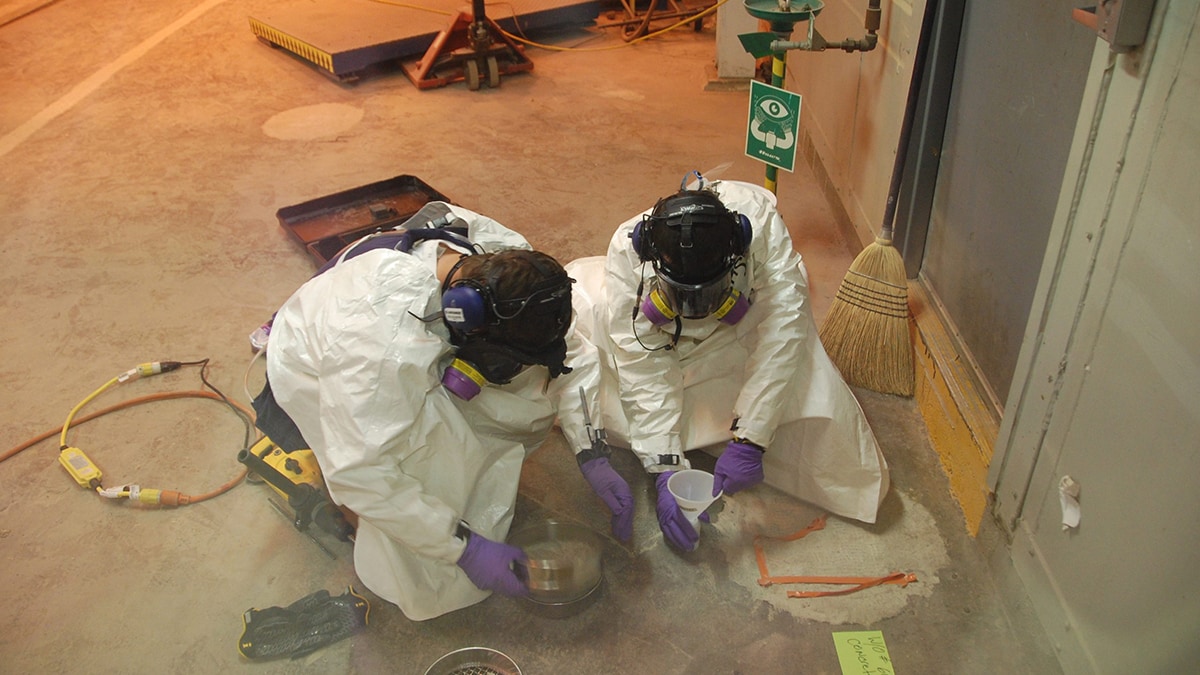 Two chemical agent workers sampling the building concrete during closure.