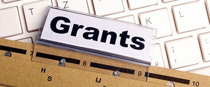 A folder labeled grants sits on a keyboard.