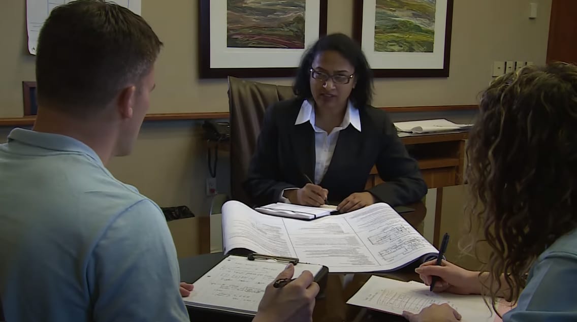 Three people sitting around a table working on describing a building water system.