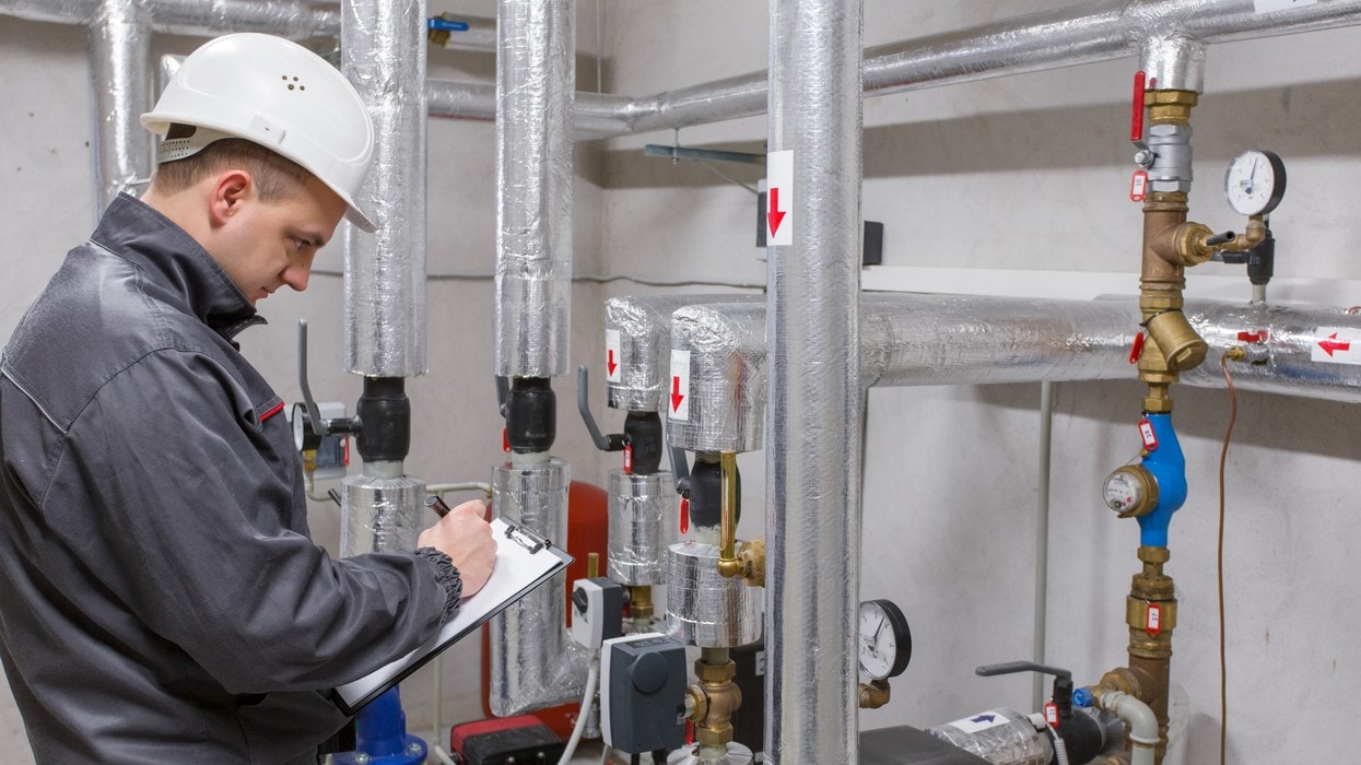 Man in a hard hat assessing water pipes.