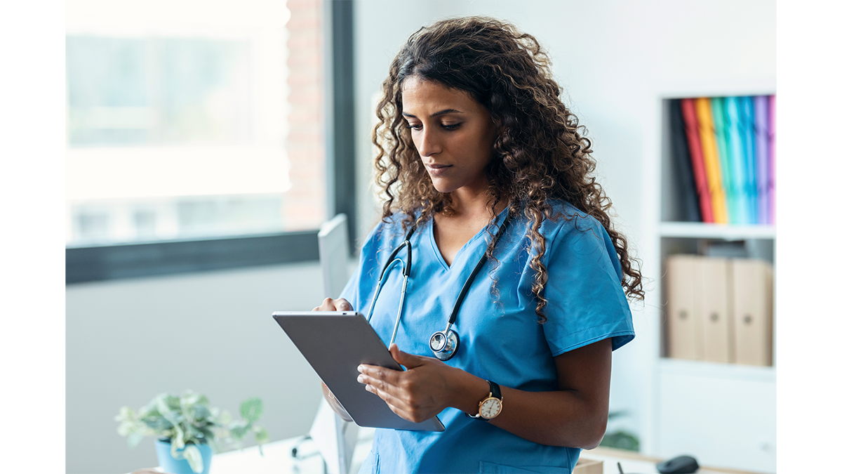 A healthcare provider reading from a tablet in their office.