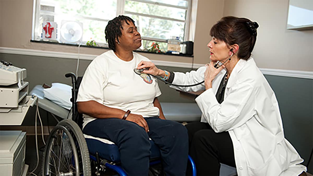 Female doctor examining a female patient who is in a wheelchair