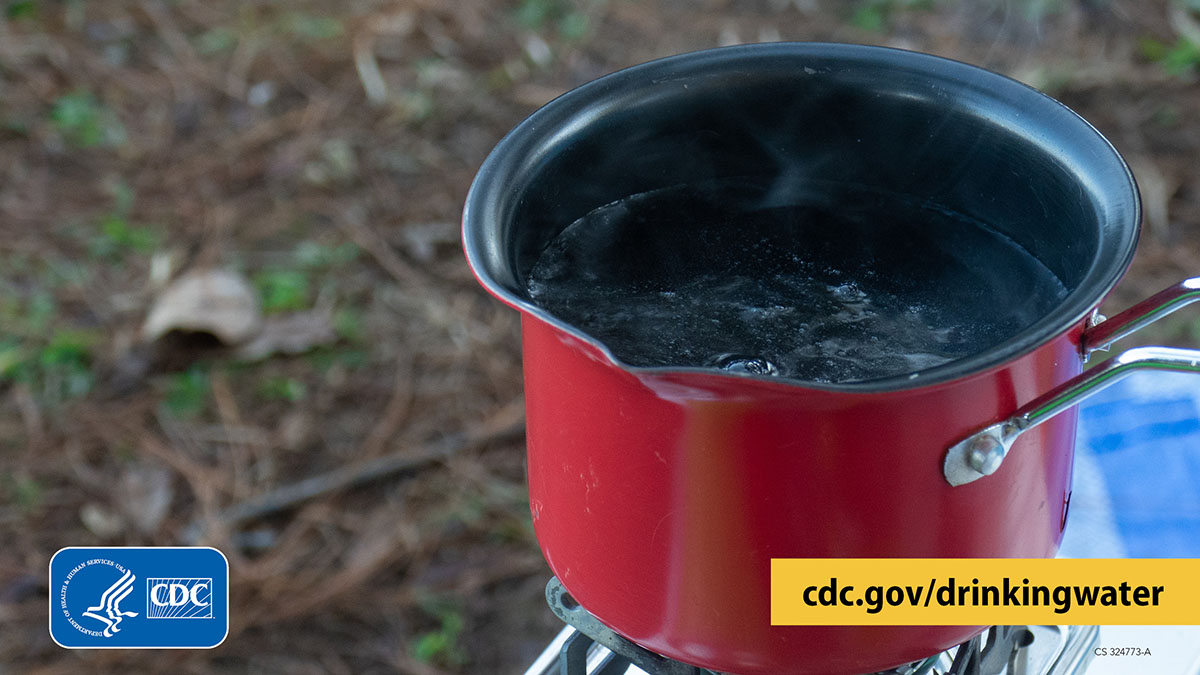 Pot of boiling water on a small, portable gas stove outside.