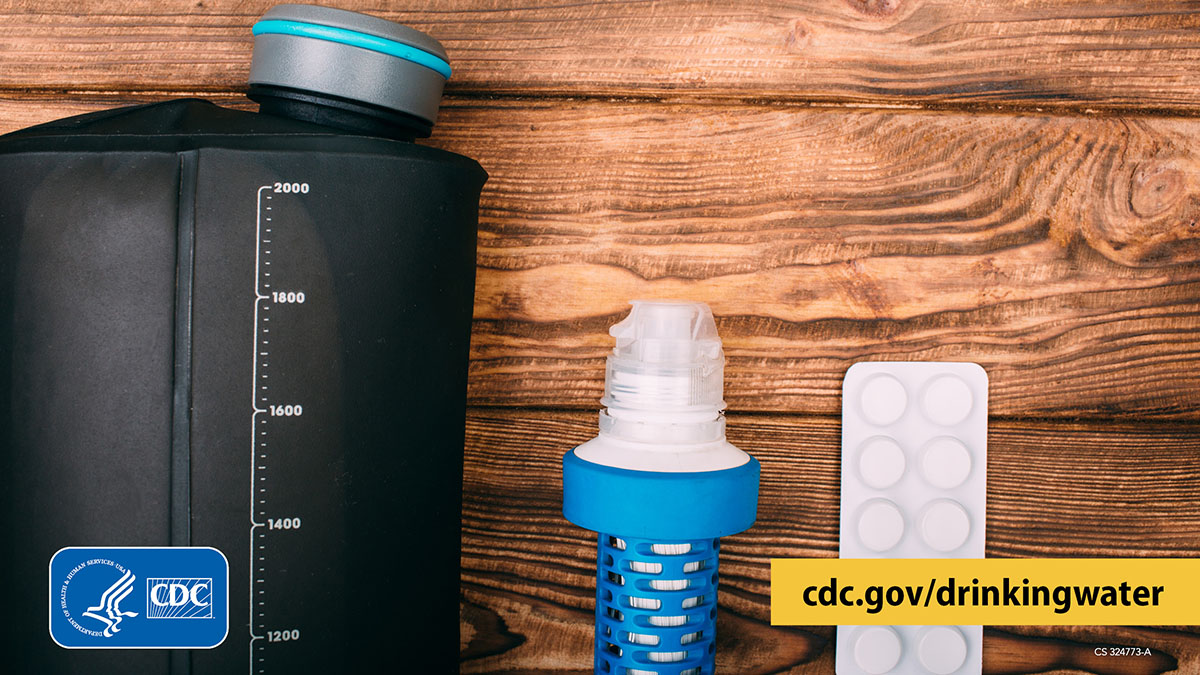 Water container with volume markings, water filter cartridge, and water disinfectant tablets on a wooden surface.