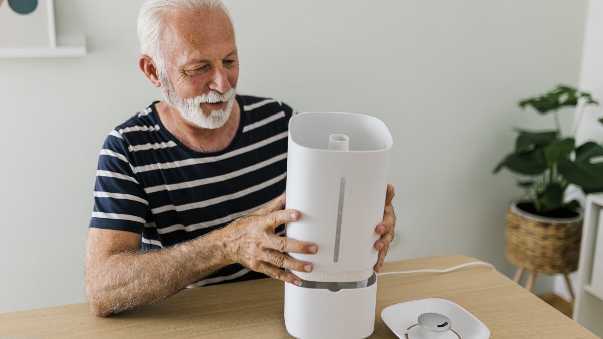 Person lifting up part of the main body of a portable humidifier