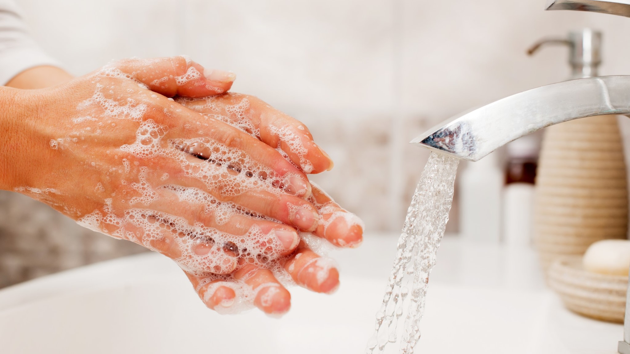 A person washing their hands with soap and water in a sink.