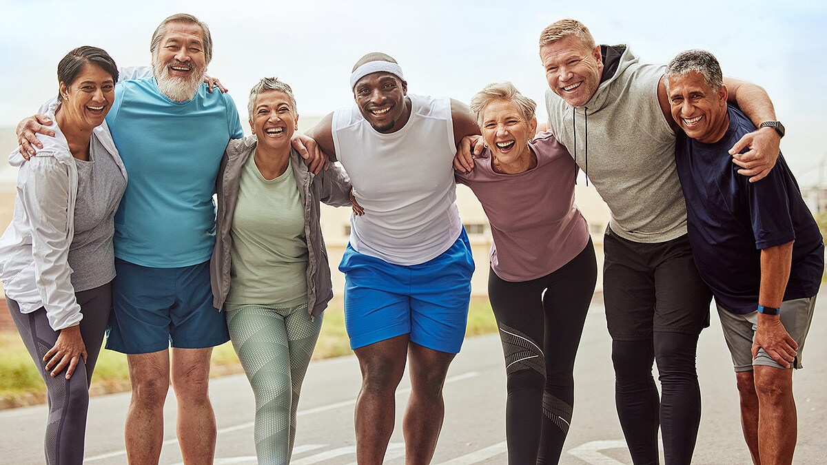 Age-, gender-, and racially-diverse group of seven posing with arms around each other after a run.