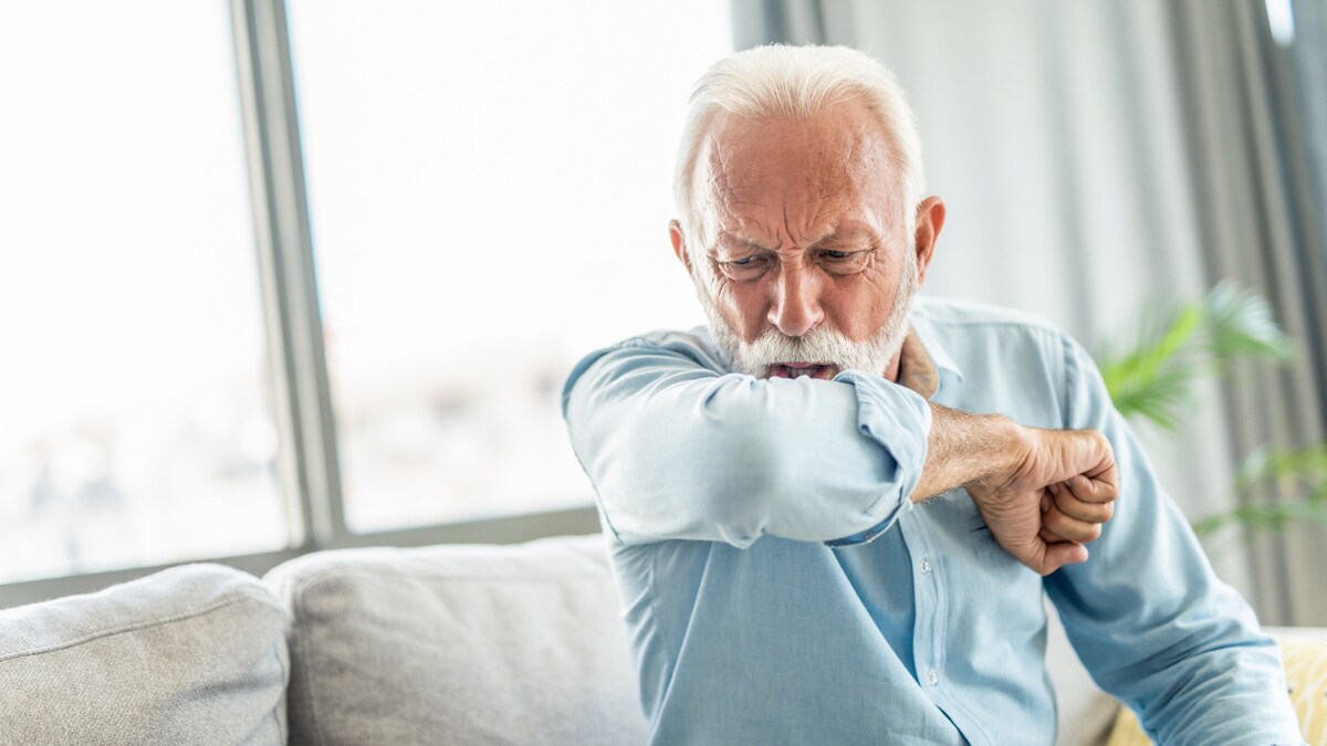 Elderly man coughing into his elbow