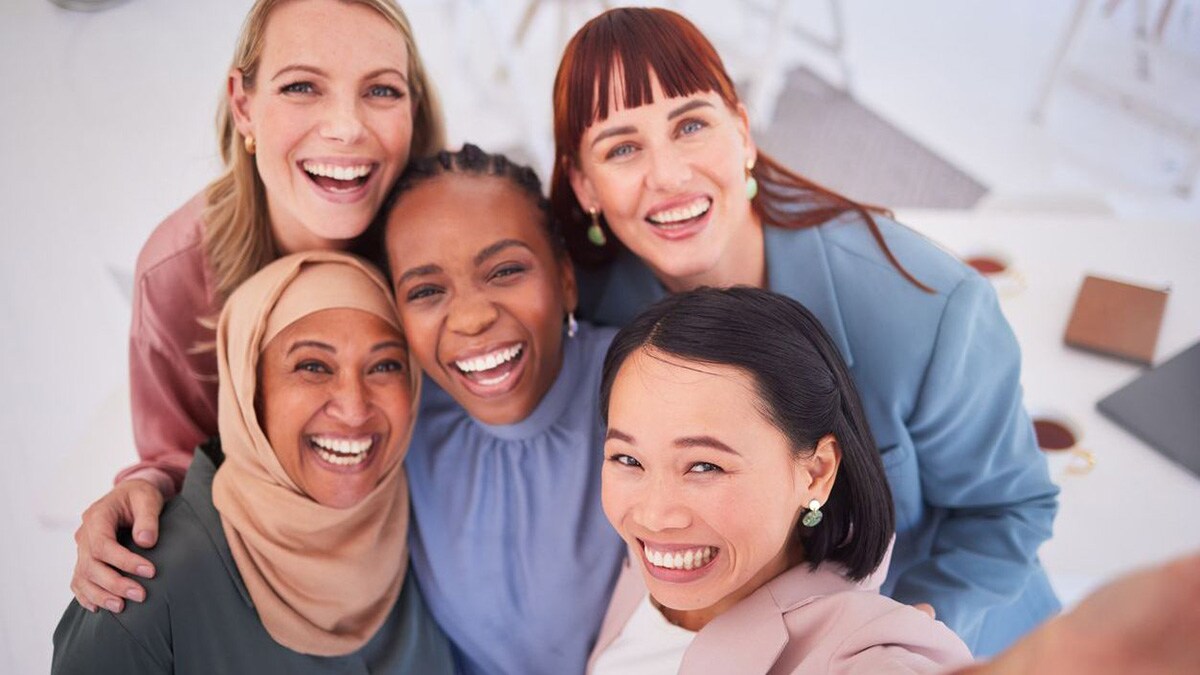 Five women standing closely together and smiling