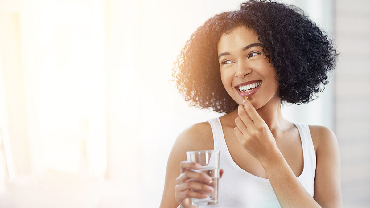 Woman taking a folic acid vitamin with a glass of water.