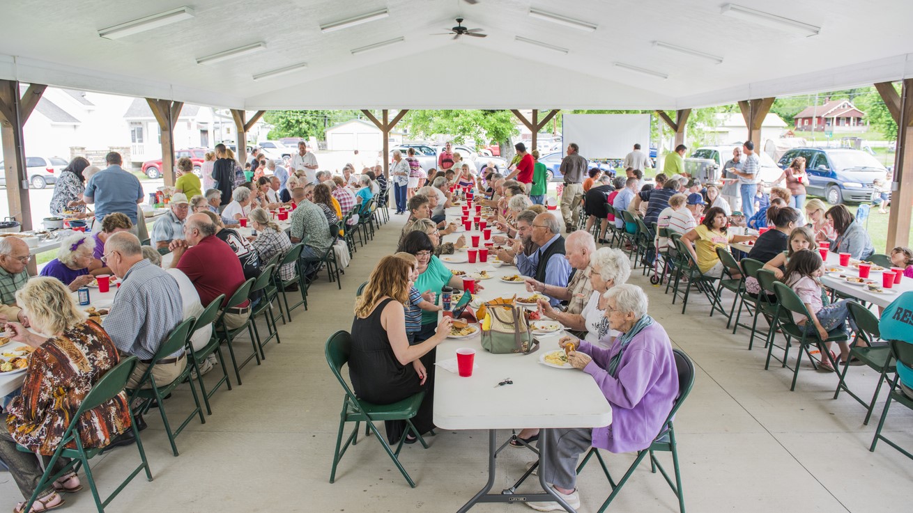 — title missing — A congregation eating at table at a church potluck.