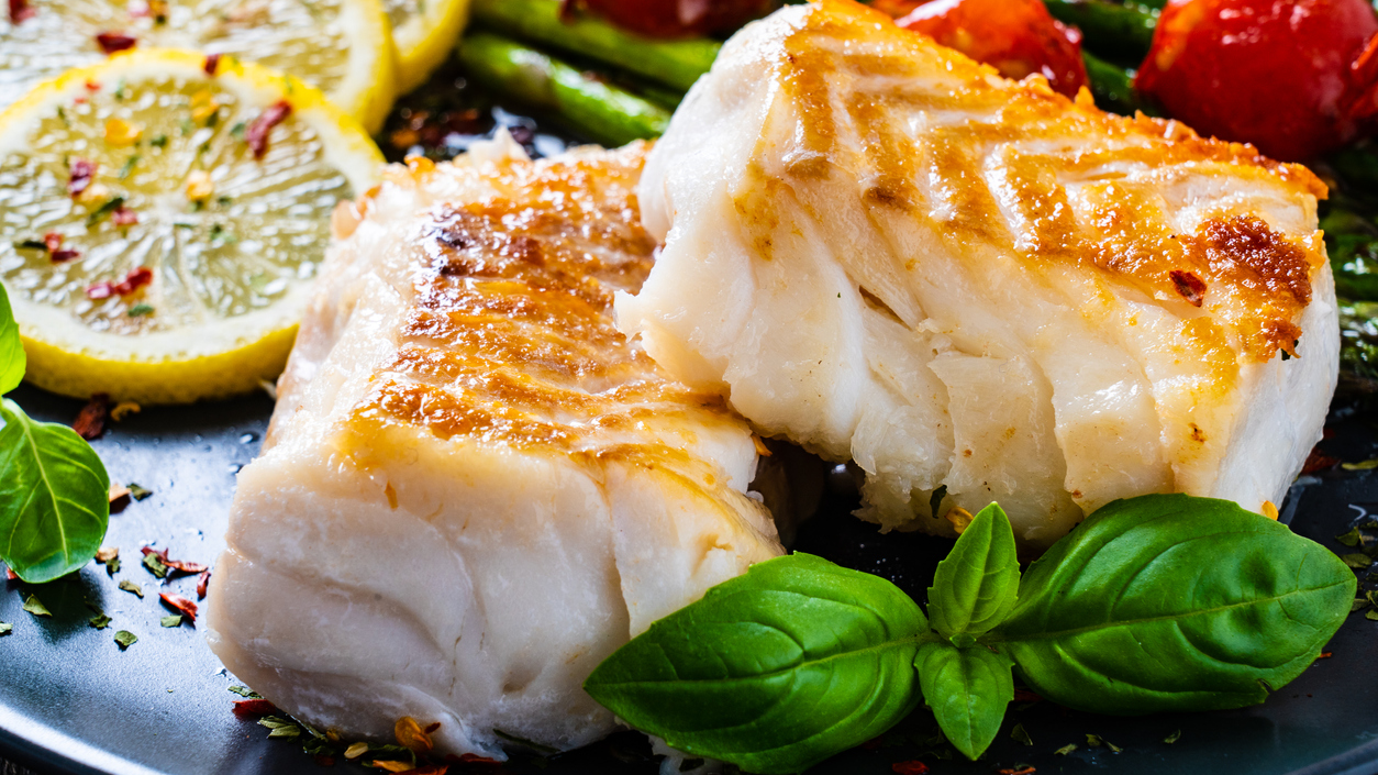 Cooked fish entree plated with lemons and herbs
