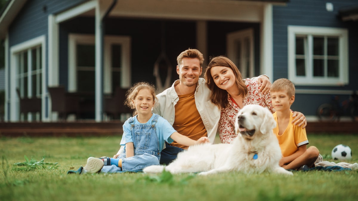 Familia sonriente sentada toda junta con su perro.