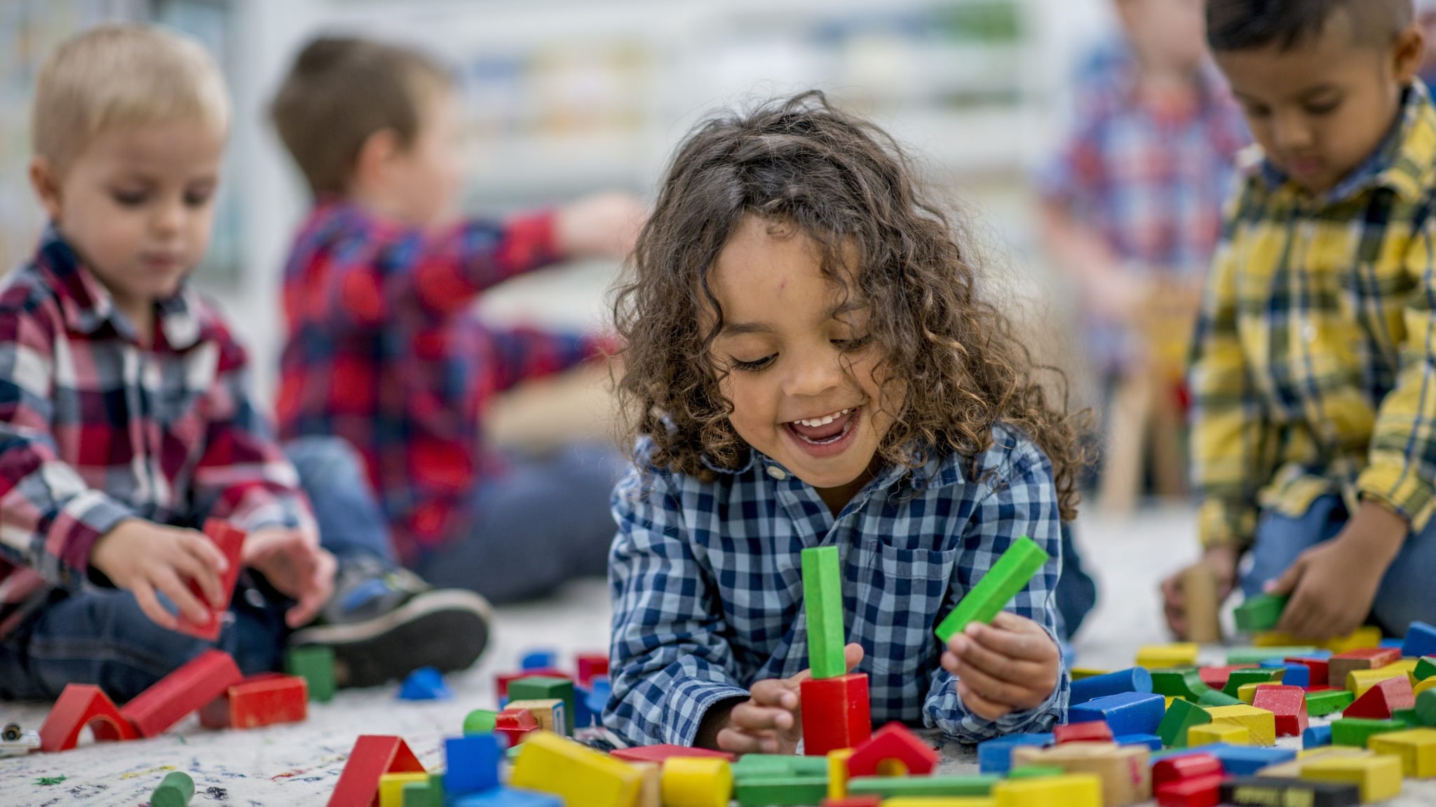 Five young children playing with blocks and other toys