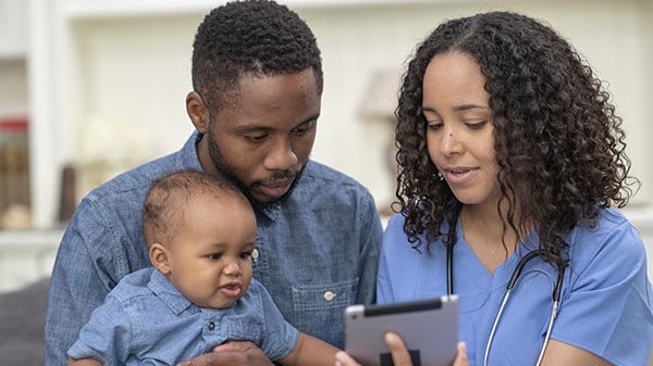 Parent and child looking at a tablet with a healthcare provider