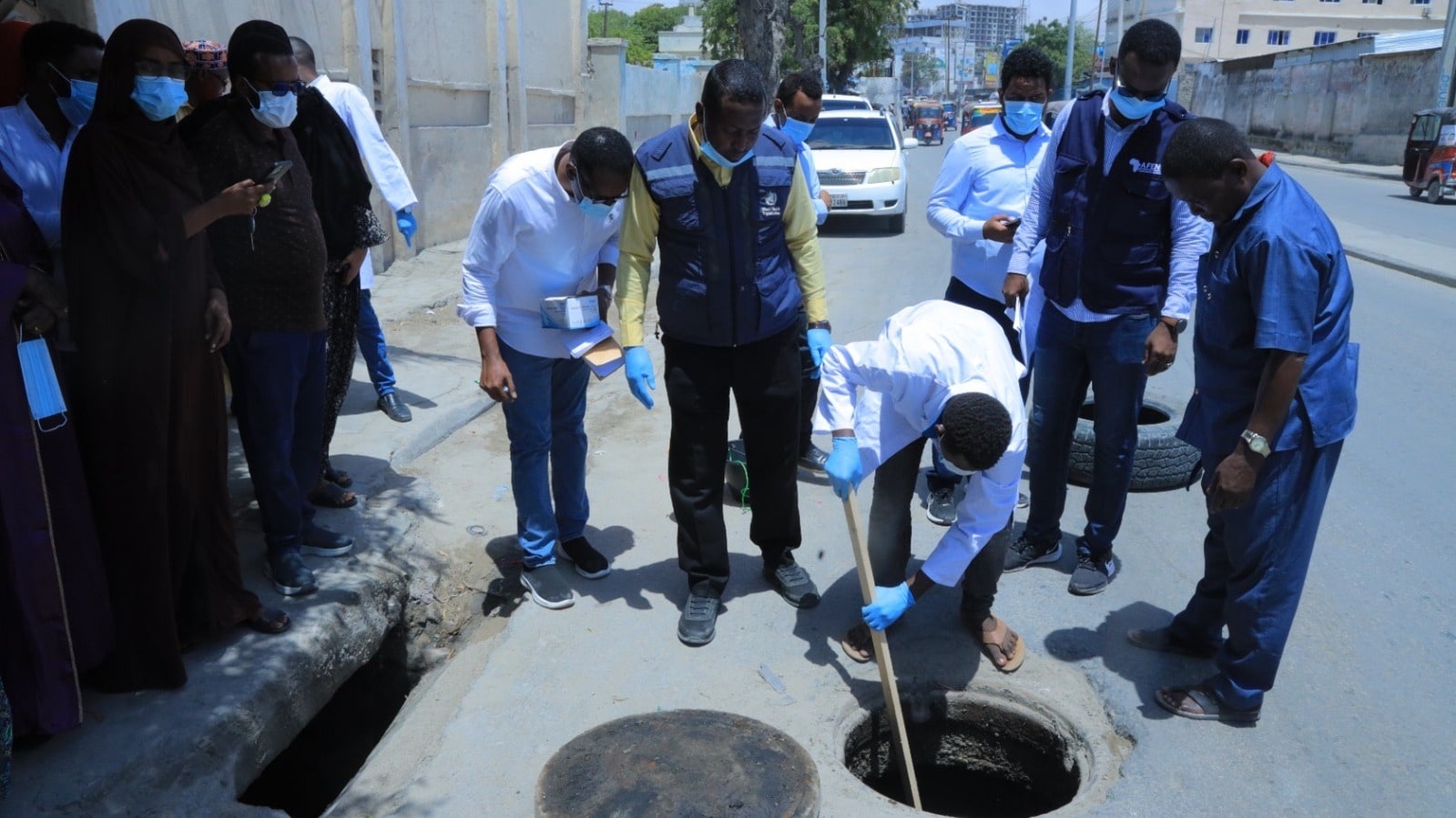 A group of individuals in blue gloves and face masks collecting environmental samples