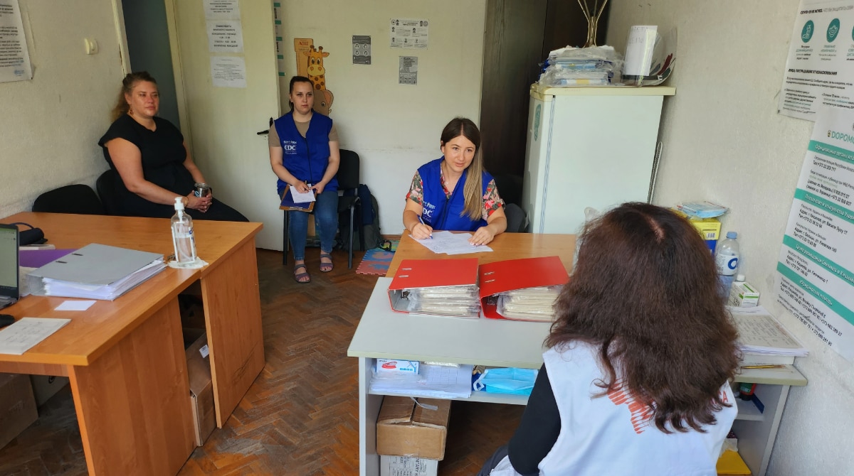 Three FETP residents speak with a woman in an office