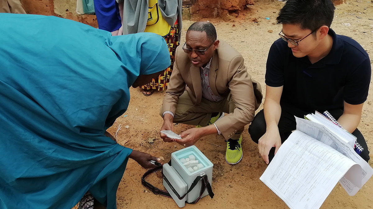 Trabajador de primera línea con vacunas hablando con mentores para revisar los contenidos de la caja con vacunas junto a un vacunador de primera línea durante una campaña contra la poliomielitis en el estado de Sokoto, en Nigeria.