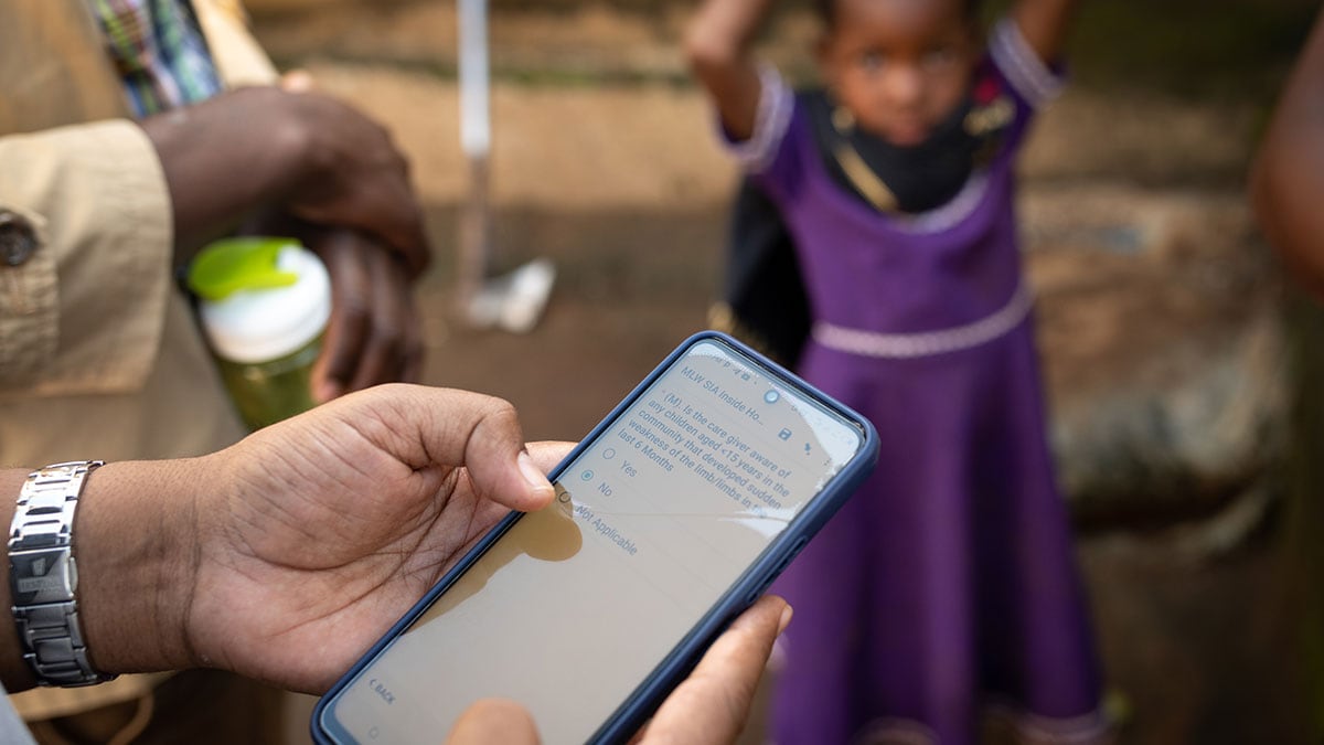 A man uses an app on a mobile phone while a girl waits.