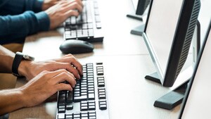 Monitors and keyboards side by side with hands typing on the keyboards.