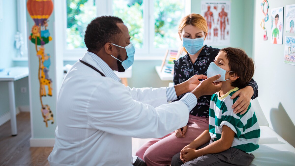 Pediatrician treats child patient while the patient's mother observes.