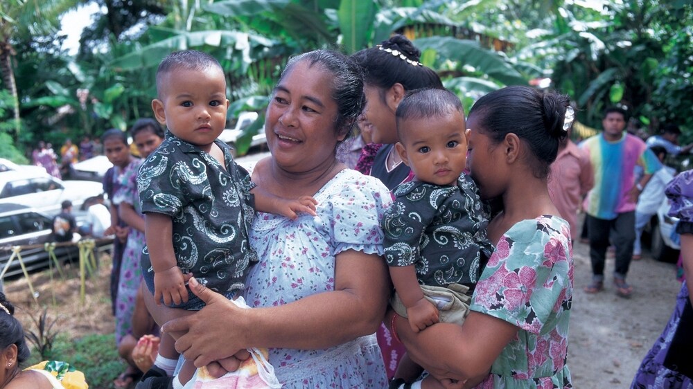 Two women in an island setting with their young children.