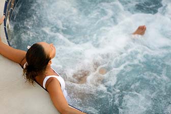 Mujer sentada en un jacuzzi, de espaldas a la cámara.