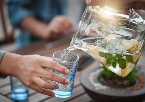 A pitcher of fruit-infused water filling a glass.