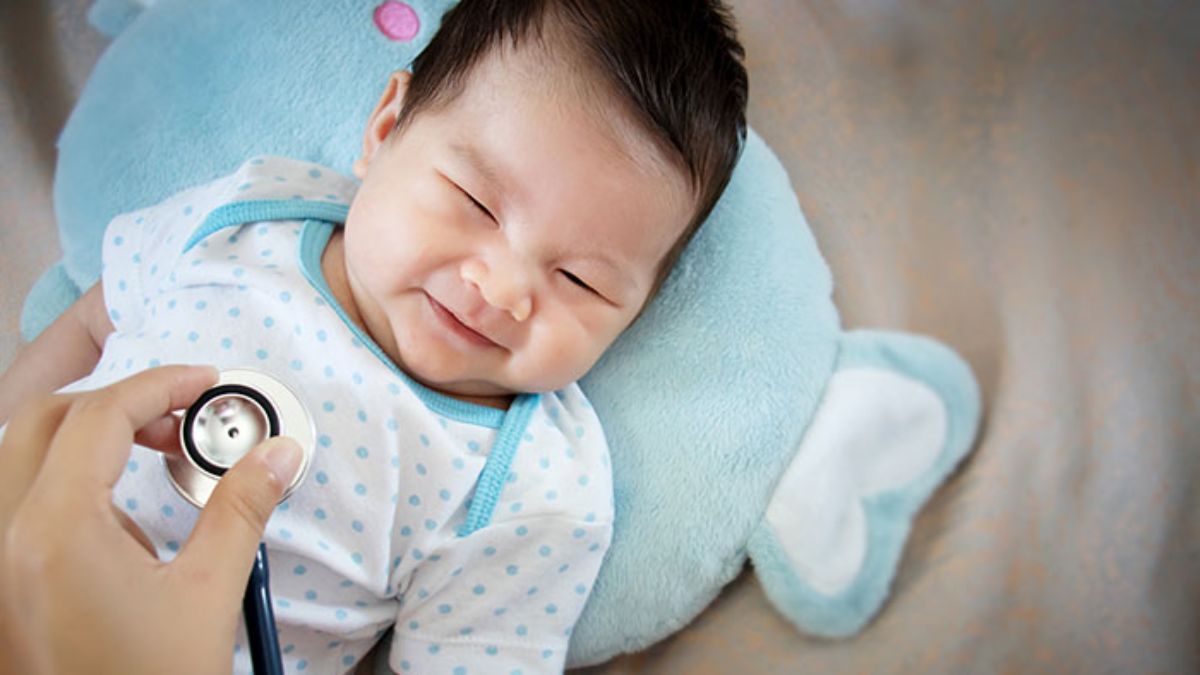 Doctor listening to toddler's heart while toddler is laying on stuffed animal