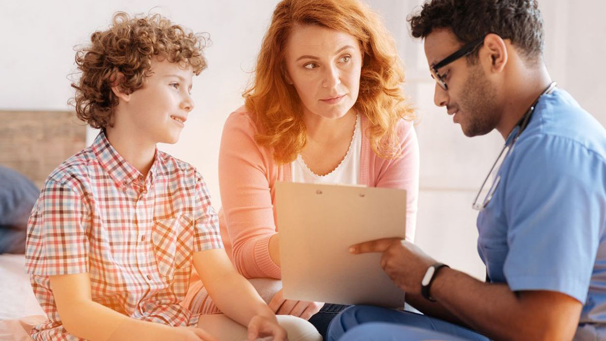Doctor reviewing chart with a mother and son