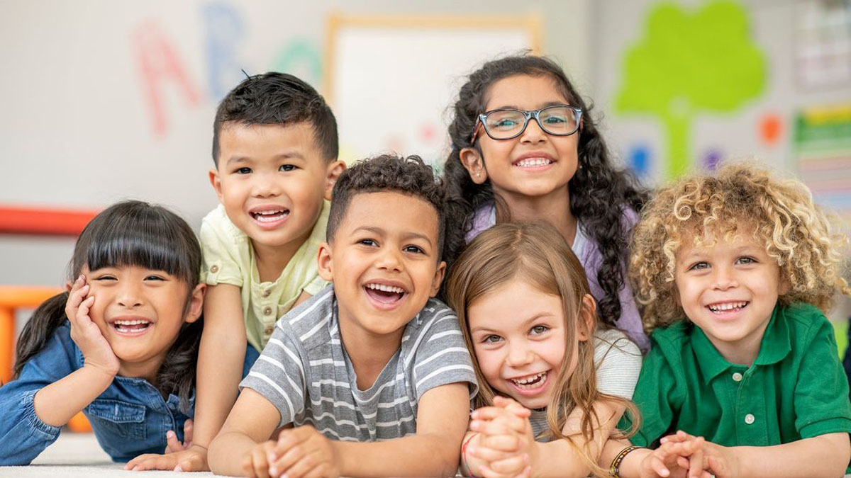 Group of kids posing and smiling in classroom