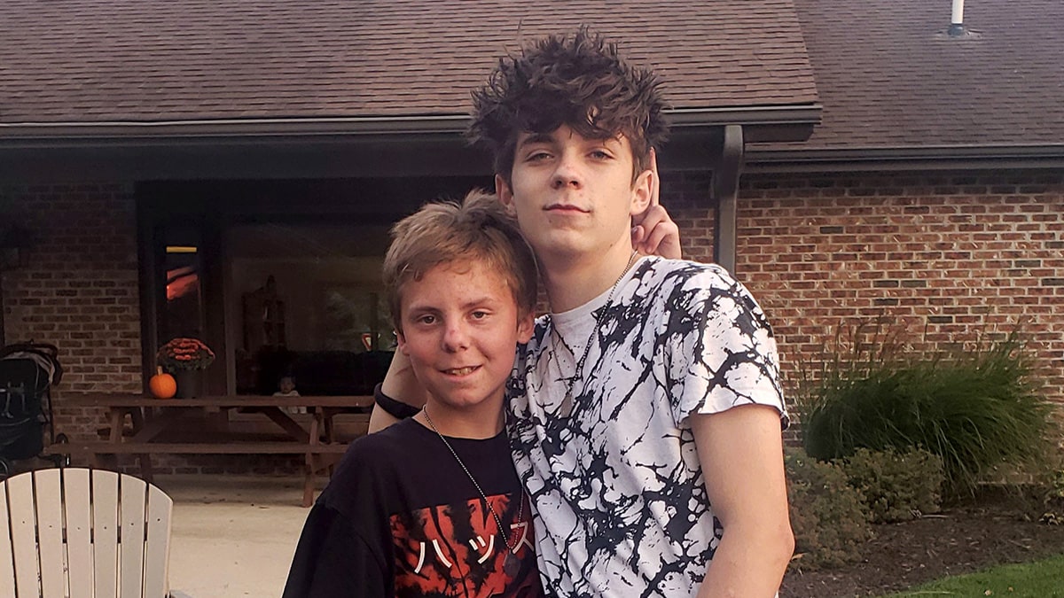 Two teenage boys standing side by side smiling