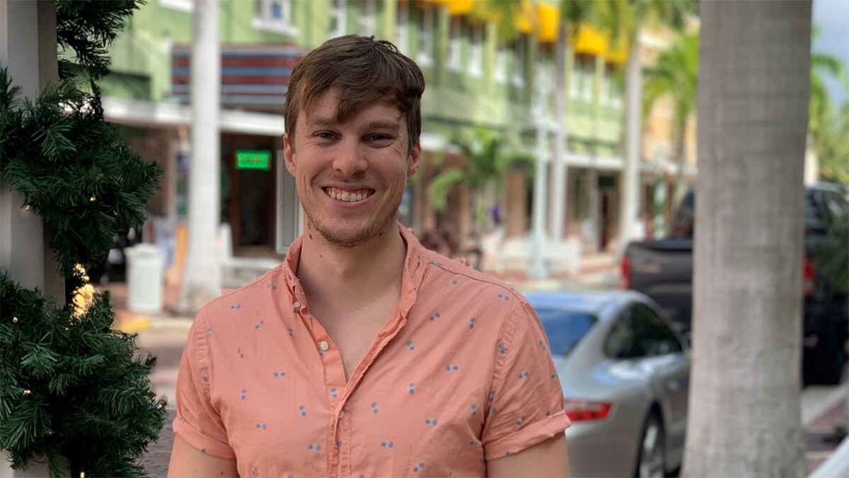 Young man standing on a sidewalk smiling