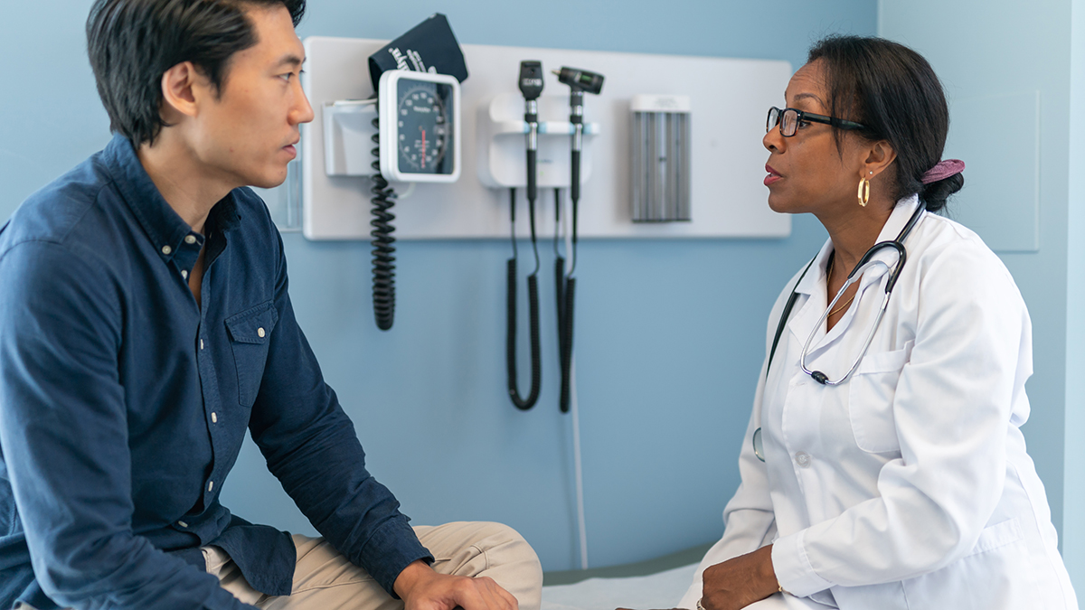 A patient sitting on an exam table speaking with a healthcare professional