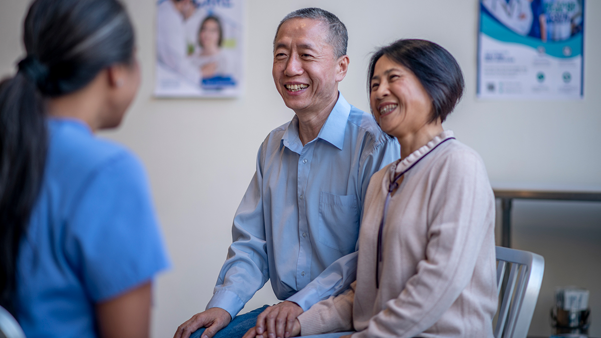 A man and a woman sitting in a doctor's office speaking with a medical professional