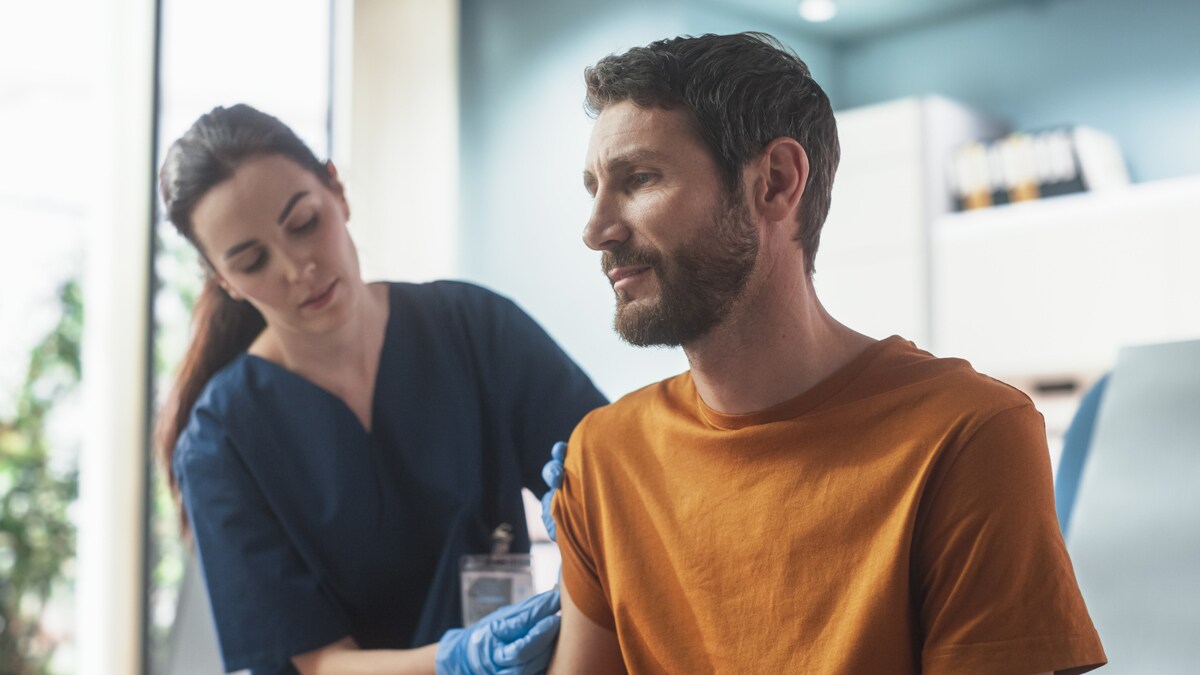 A doctor giving a man a shot in the arm in a doctor's office