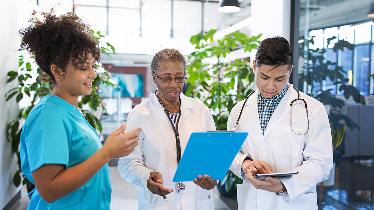 A group of doctors looking at charts on a blue clipboard