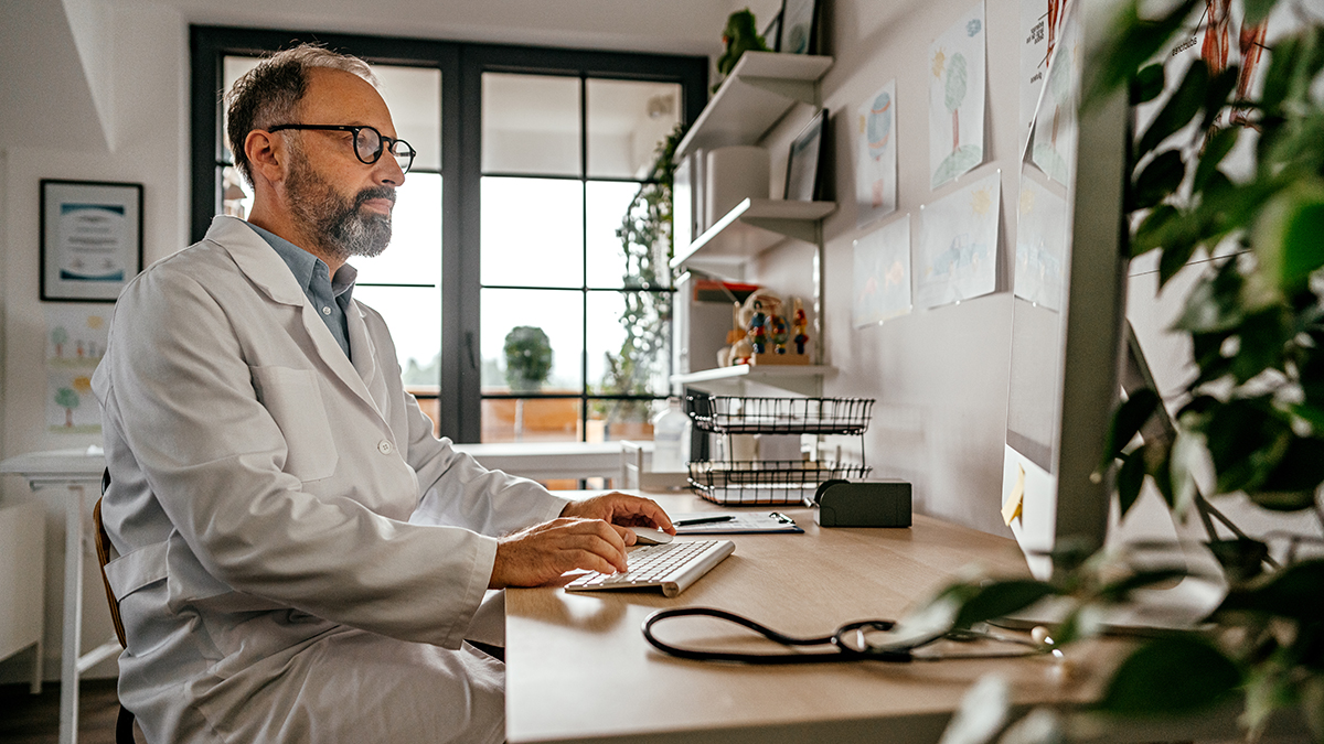 Doctor sitting at a desk reviewing hepatitis c testing recommendations for perinatally exposed infants and children